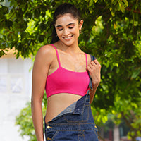Woman wearing a bright pink beginner bra with denim overalls outdoors