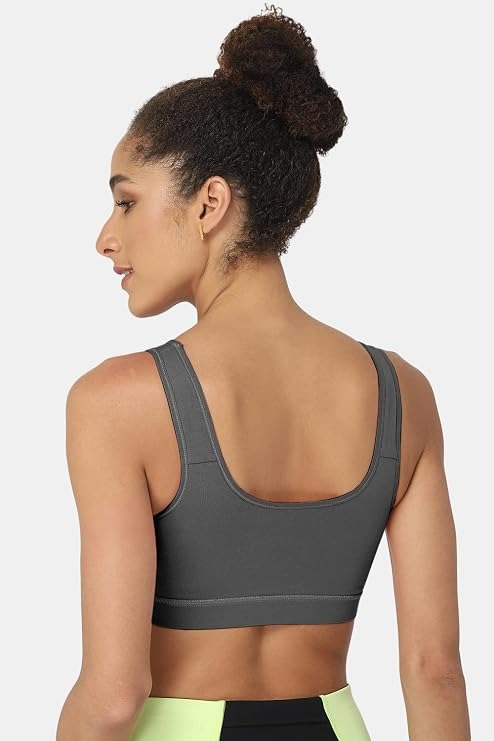A woman shown from the back wearing a dark gray sports bra, with her hair in a high bun, against a light gray studio background.